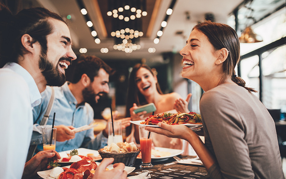 Freunde im Lachen und genie&szlig;en gutes Essen in einem der Restaurants auf einem Kreuzfahrtschiff